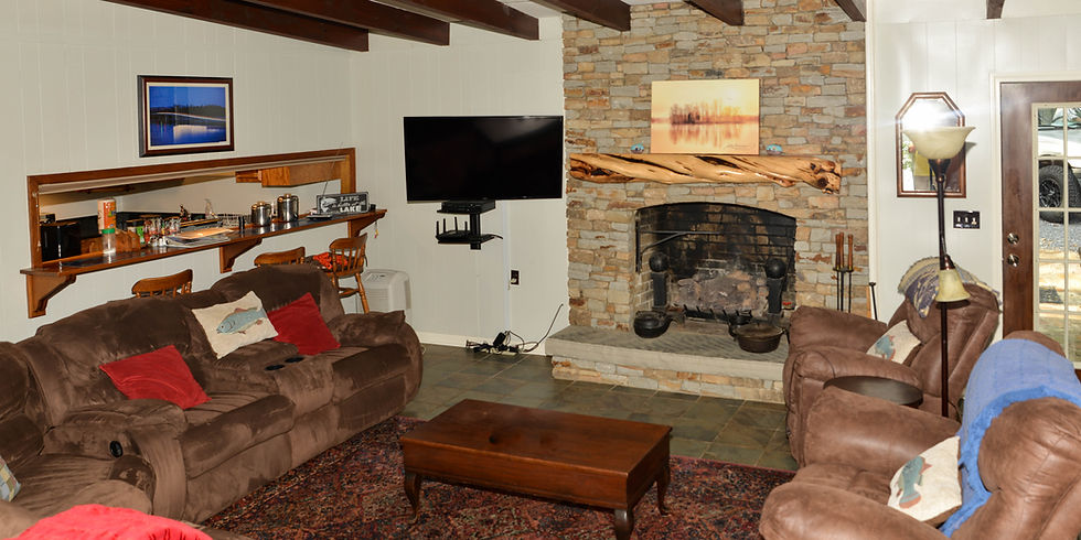Living room with stone fireplace, flat-screen TV, and reclining sofas at Guntersville Getaway lake house