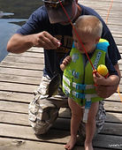 Child in life jacket fishing from the dock with an adult at Guntersville Getaway on Lake Guntersville