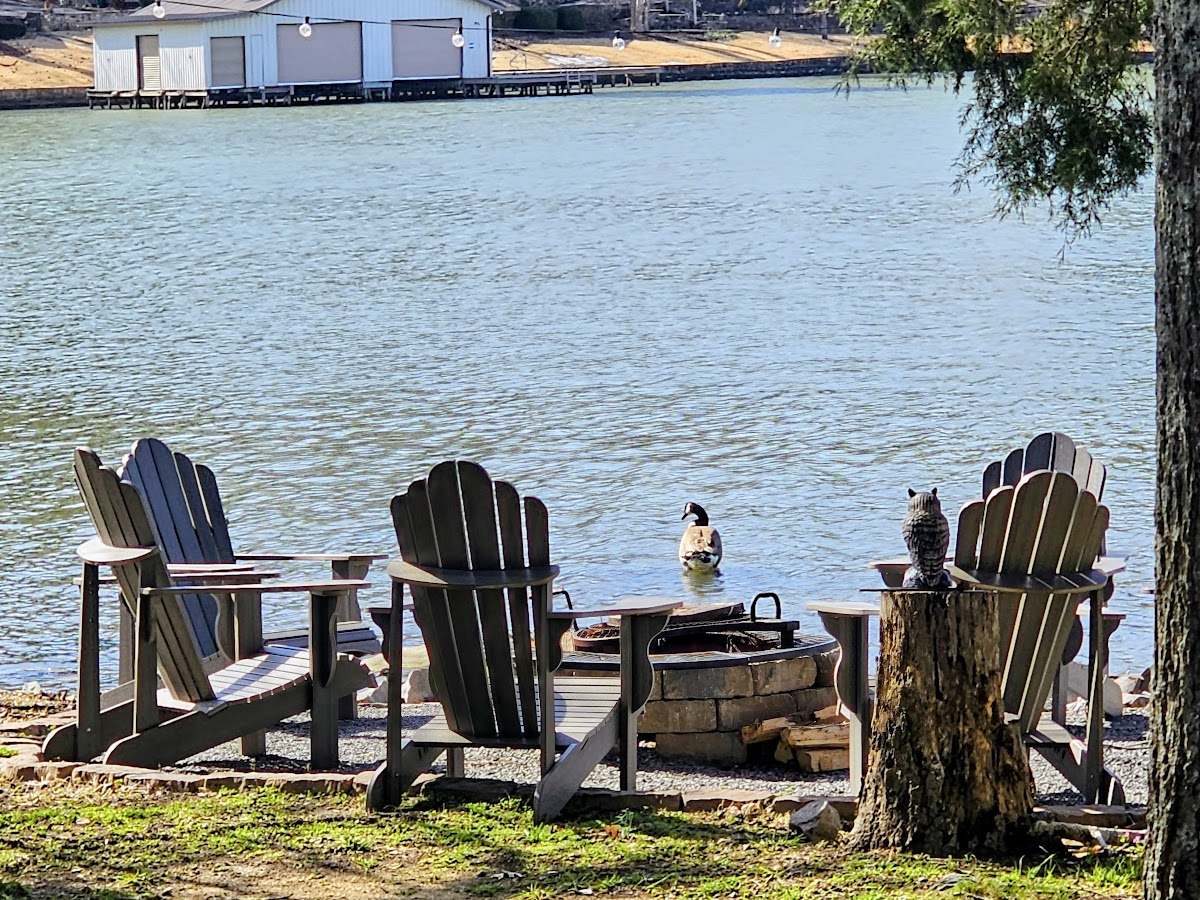 Adirondack chairs around the stone fire pit overlooking the calm cove at Guntersville Getaway on Lake Guntersville