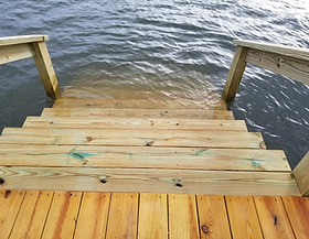 Dock steps with wooden handrails leading into the calm cove at Guntersville Getaway for safe lake access