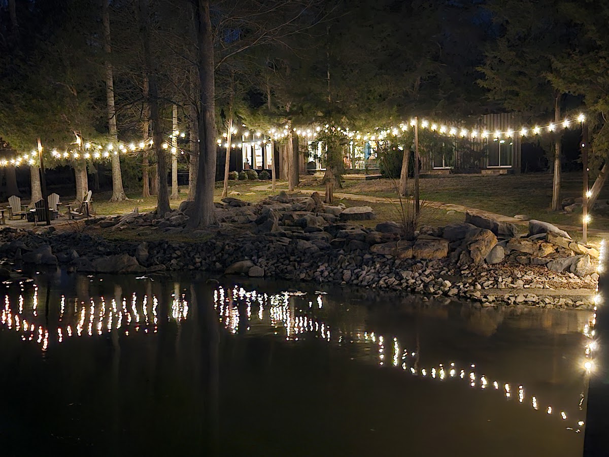 Guntersville Getaway lakefront property illuminated by string lights reflecting on the water at night